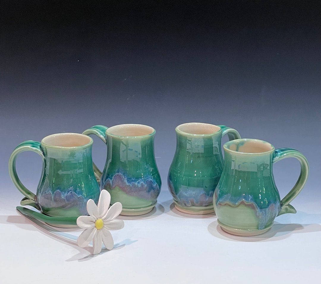 A group of four cups and saucers with a flower.